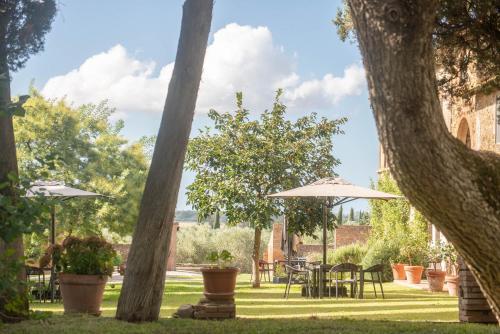 a garden with tables and chairs and umbrellas at Tenuta di Poggio Cavallo in Istia dʼOmbrone