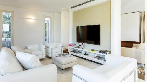 a living room with white furniture and a flat screen tv at VILLA LE MANDRIE 7&2, Emma Villas in Castiglione della Pescaia