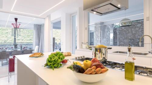 a kitchen with a counter with a bowl of fruit on it at VILLA LE MANDRIE 7&2, Emma Villas in Castiglione della Pescaia