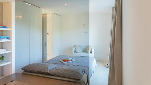a bedroom with a bed and a chair and a mirror at VILLA LE MANDRIE 7&2, Emma Villas in Castiglione della Pescaia