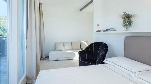a bedroom with a bed and a chair next to a window at VILLA LE MANDRIE 7&2, Emma Villas in Castiglione della Pescaia