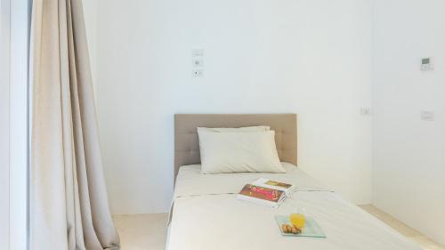 a bed with a book on it next to a window at VILLA LE MANDRIE 7&2, Emma Villas in Castiglione della Pescaia