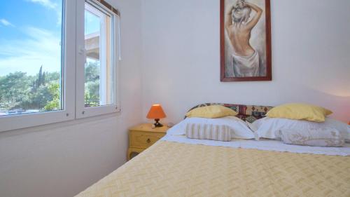 a white bedroom with a bed and a window at Apartment Slatina Bay in Vela Luka