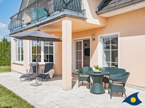 a patio with a table and chairs and an umbrella at Haus Achterwasserblick in Ueckeritz