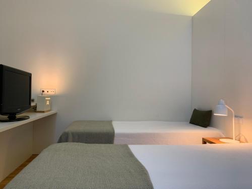a bedroom with two beds and a tv in it at Convento das Bernardas AZ in Tavira