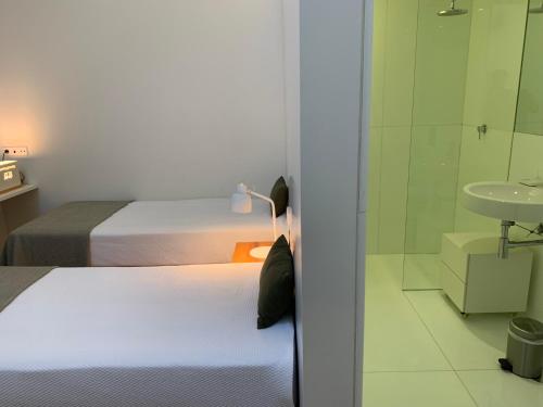 a bedroom with two beds and a bathroom with a sink at Convento das Bernardas AZ in Tavira