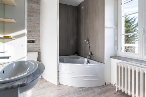 biała łazienka z wanną i umywalką w obiekcie Gîte le Couderc w mieście Gabriac