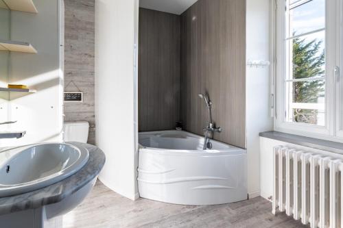 a white bathroom with a tub and a sink at Gîte le Couderc in Gabriac
