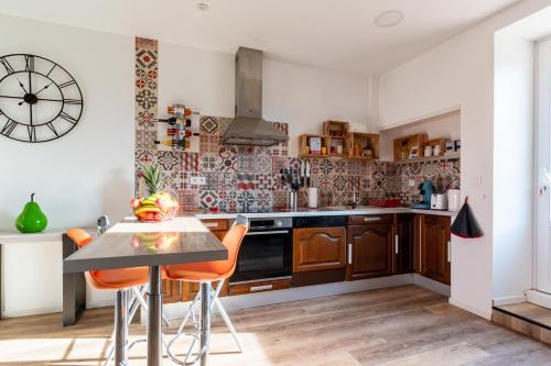 a kitchen with a table and chairs and a clock on the wall at Gîte le Couderc in Gabriac