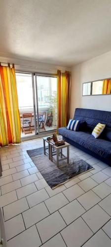 un salon avec un canapé bleu et une table dans l'établissement Studio Loggia Plage: 2 min à pied à Port-Argelès, à Argelès-sur-Mer