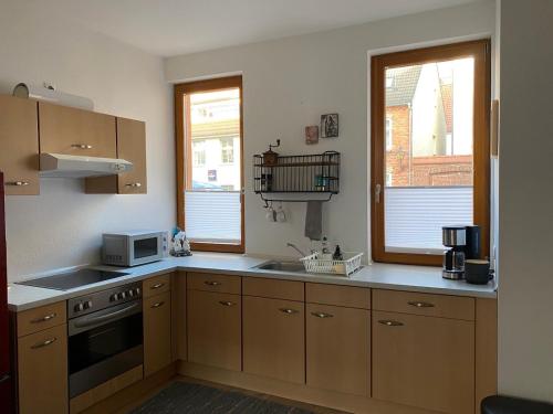 eine Küche mit Holzschränken, einer Spüle und einer Mikrowelle in der Unterkunft Hofquartier in Rostock