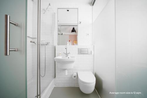 a white bathroom with a toilet and a sink at Numa Madrid Script in Madrid