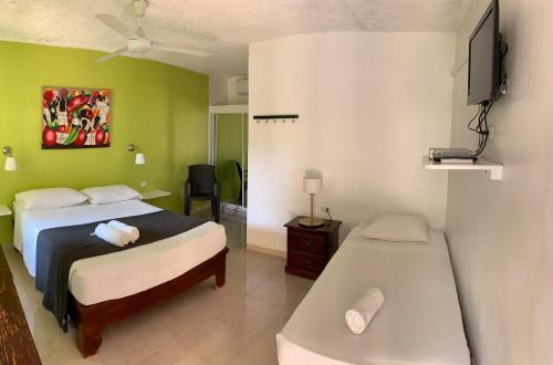 a bedroom with two beds and a flat screen tv at Hotel Pedernales Italia Republica Dominicana in Pedernales