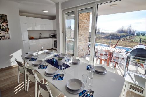 a dining room with a white table and a large window at Villa Miri II in Privlaka