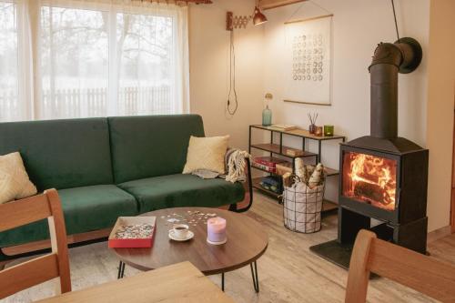 a living room with a green couch and a wood stove at Zielony domek nad Marychą w Budwieć in Stanowisko