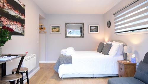 a bedroom with a white bed and a desk at 13 Matheson Place in Portree