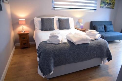 um quarto com uma cama com toalhas e uma cadeira azul em 13 Matheson Place em Portree
