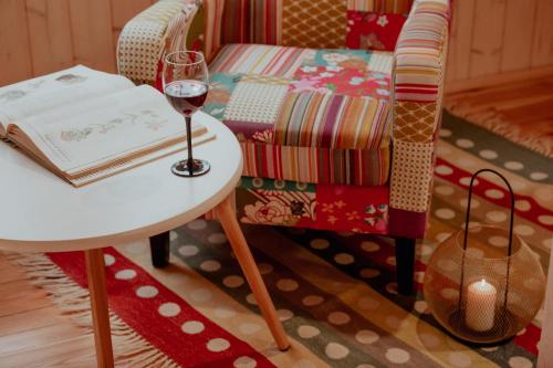 a glass of wine sitting on a table next to a chair at Zielony domek nad Marychą w Budwieć in Stanowisko