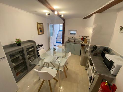 a kitchen with a glass table and white chairs at Amiais River Beach House in Amiães de Baixo