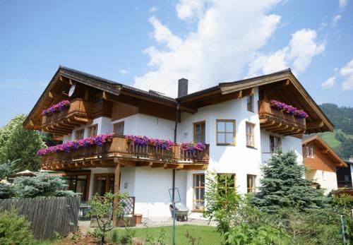 una casa blanca con flores en los balcones en Hotel Landhaus Zell am See en Zell am See