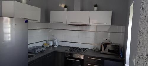 una pequeña cocina con armarios blancos y fregadero en BE-LE-VALÓ APARTMAN en Szécsény