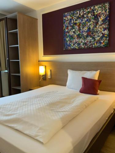 a bedroom with a large white bed with a painting on the wall at RheinHotel ARTE in Remagen