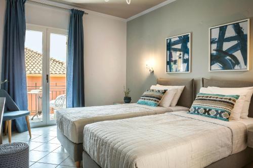 two beds in a bedroom with a balcony at Makis Hotel in Skala Kefalonias