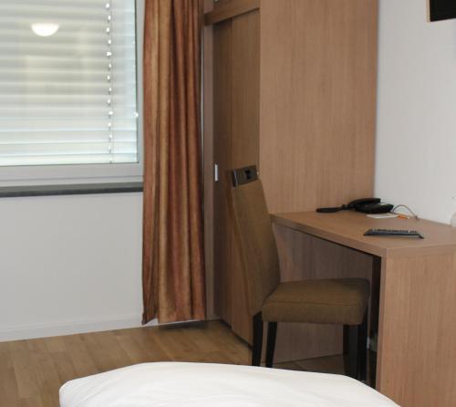 a room with a desk and a chair and a bed at Apartment Hotel am Sand in Hamburg