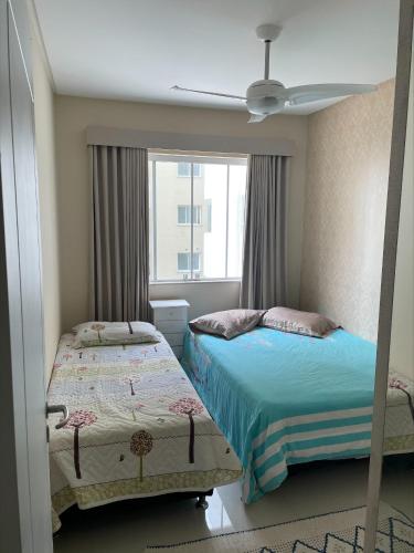 una camera da letto con due letti e una finestra di Apartamento em Capão da Canoa 1 quadra do mar a Capão da Canoa