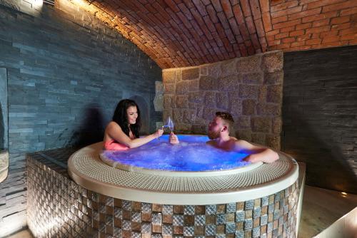 Un uomo e una donna seduti in una vasca idromassaggio di Hotel Stará Pekárna s privátním wellness a Liberec