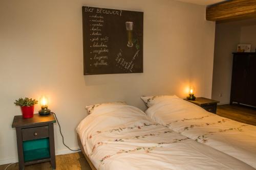 a bed in a room with two candles on tables at 't Brouwershuis in Leende