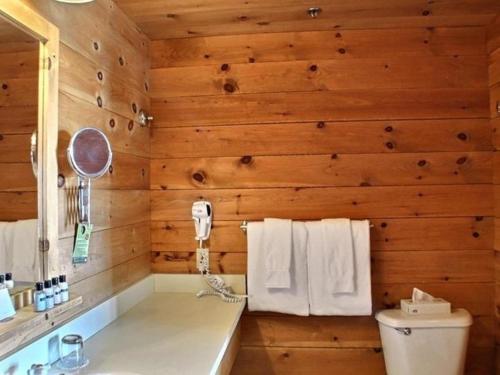 Łazienka z drewnianymi ścianami, toaletą i ręcznikami w obiekcie Sacacomie Hôtel et Spa w mieście Saint-Alexis-des-Monts