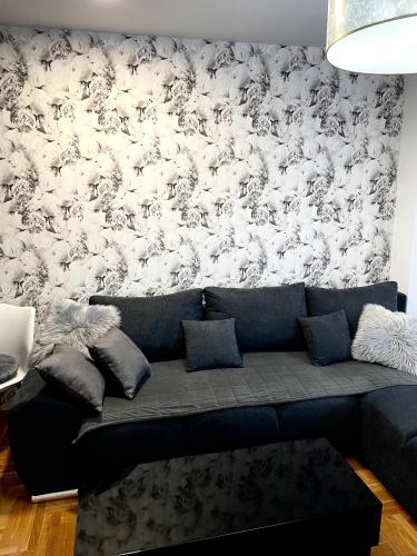 a couch in a living room with a wall covered in sheep at Apartman CITY CENTER 3-šetalište in Prijedor