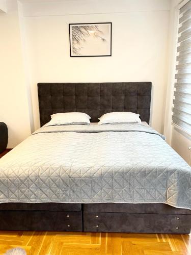 a bedroom with a large bed with a black headboard at Apartman CITY CENTER 3-šetalište in Prijedor