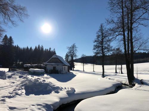 a house in the snow next to a river at Hotel a Penzion PEGAS in Nové Město na Moravě
