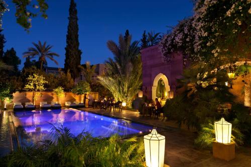 a courtyard with a swimming pool at night at Dar Rhizlane, Palais Table d'hôtes & SPA in Marrakesh