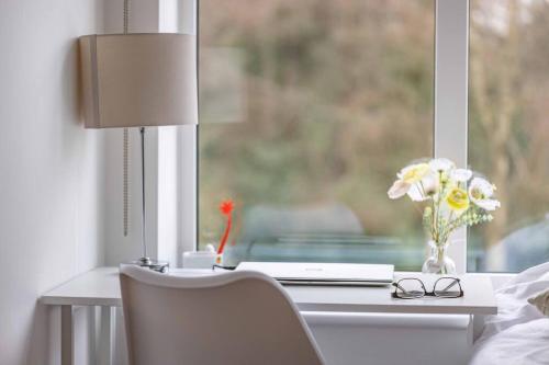 a desk with a lamp and a vase of flowers on a window at STYLISH HOME @ VIRGINIA WATER LAKE & FREE PARKING in Englefield Green