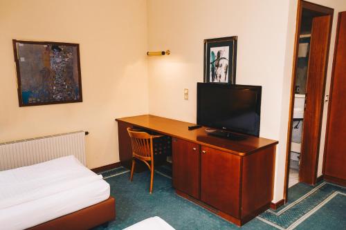 クニッテルフェルトにあるPaul's Hotelのデスク、テレビ、ベッドが備わる客室です。