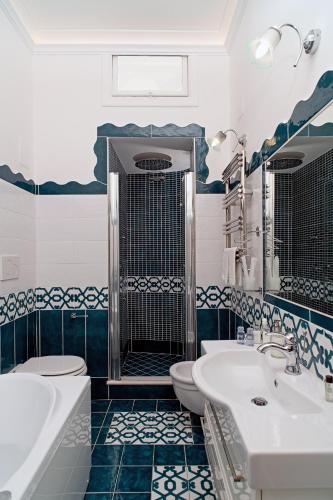a blue and white bathroom with two sinks and a toilet at Villa Fiorentino in Positano
