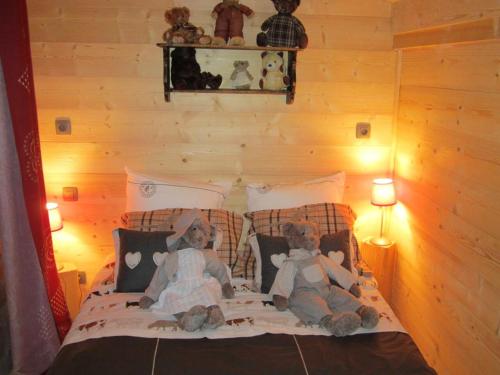 Dois ursos de peluche sentados em cima de uma cama em Villa d'une chambre avec piscine privee sauna et jardin clos a Allinges em Allinges