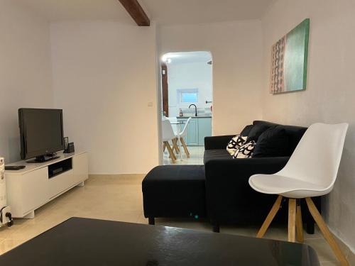 a living room with a black couch and a tv at Amiais River Beach House in Amiães de Baixo