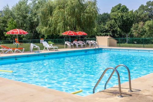 a swimming pool with chairs and umbrellas at Camping Sites et Paysages Les Prés Hauts in Sisteron