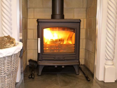 a stove in a room with a fireplace at Cosy Stone Cottage, The Bungalow Perrotts Brook in Cirencester