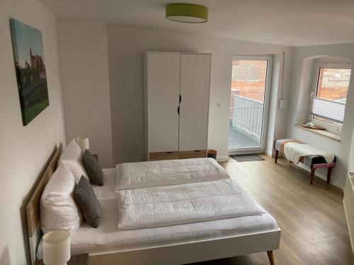 a white bedroom with two beds and a window at Das BilderbuchCafe - Ferien Apartment NO 5 - Markt 7 in Havelberg