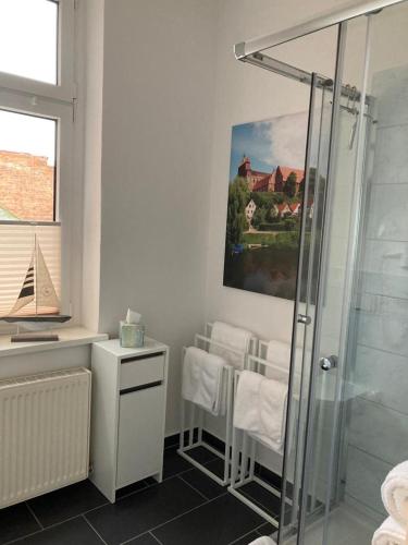 a bathroom with a shower and chairs and a painting at Das BilderbuchCafe - Ferien - Apartment NO 3 - Markt 7 in Havelberg
