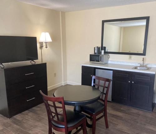 a hotel room with a table and chairs and a sink at University Inn Duke in Durham