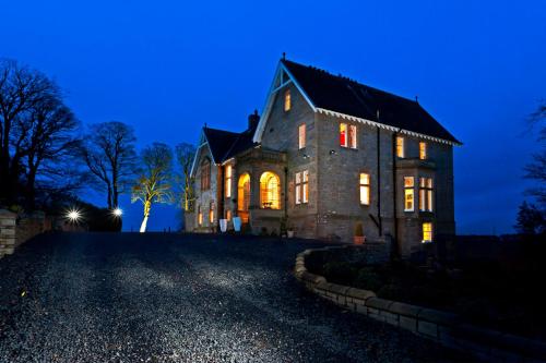 una casa vieja por la noche con las luces encendidas en Balmule House, en Dunfermline