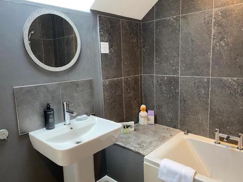 uma casa de banho com um lavatório, uma banheira e um espelho. em Stewart Hall em Dumfries