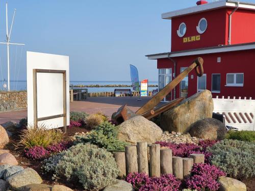 a garden in front of a light house with a sign at AnkerZeit - Wellnesswohnung in Damp in Damp