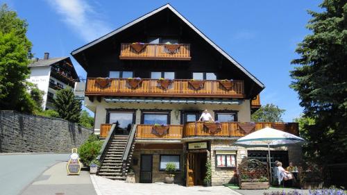 a large house with a balcony with a man sitting on the balcony at Pension Göbel in Willingen